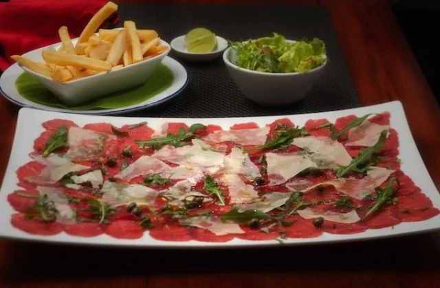 Carpaccio de bœuf servi avec roquette et copeaux de parmesan.