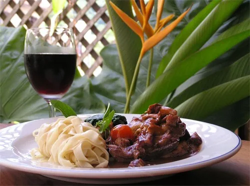 Coq au vin accompagné de pâtes.